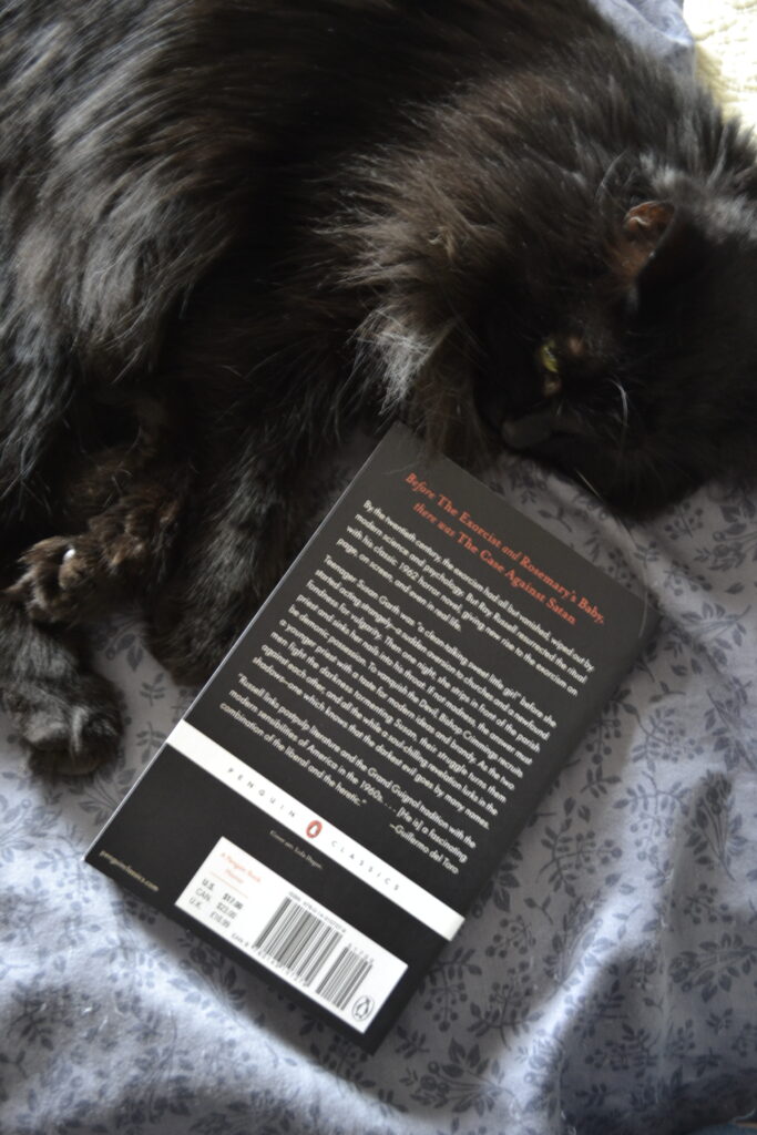 A black cat curls around The Case Against Satan.