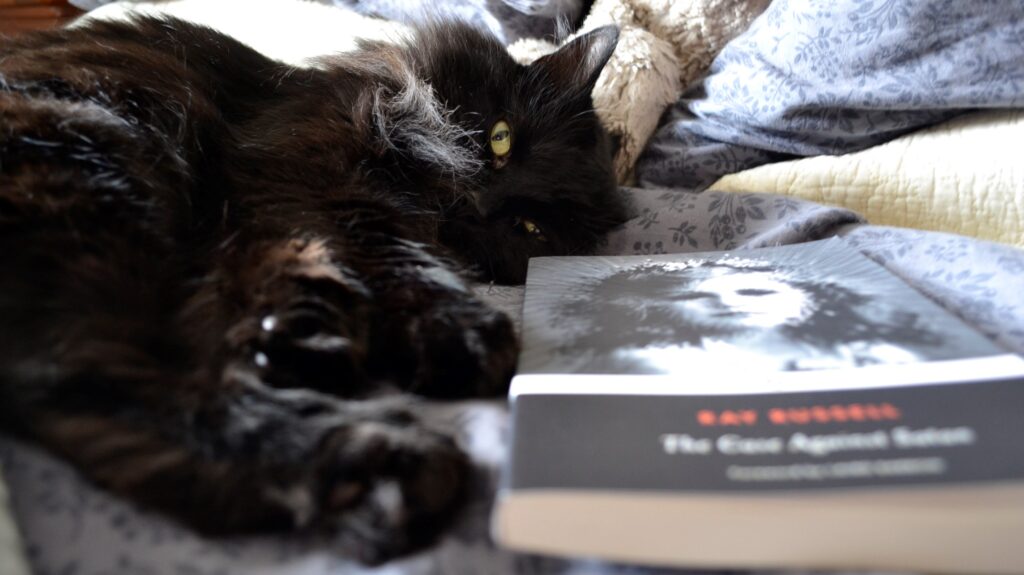 A black cat lies beside The Case Against Satan.