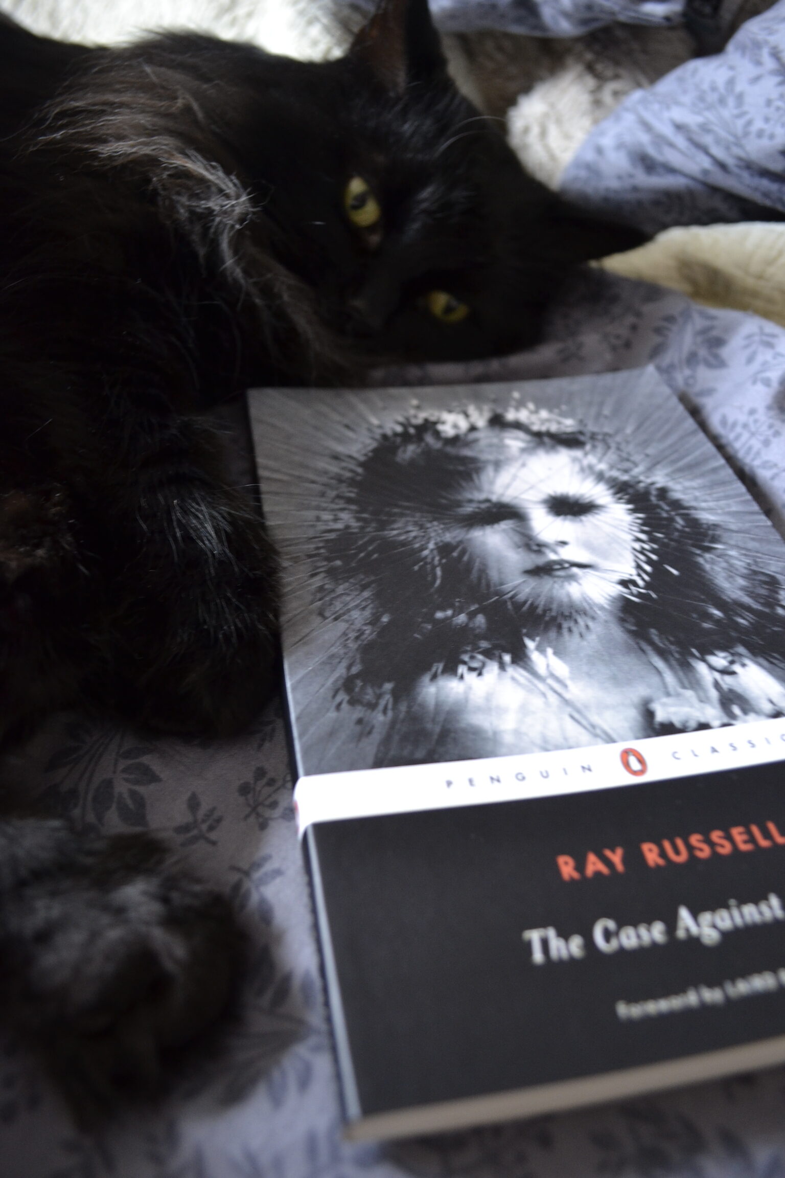 A black cat lies beside The Case Against Satan.