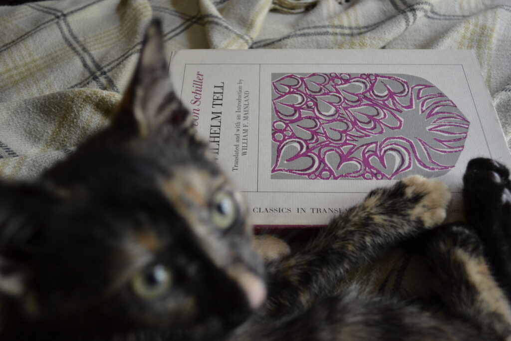 A tortoiseshell cat beside Schiller's Wilhelm Tell.