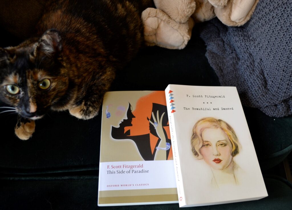 A tortoiseshell kitten sits beside two books by the Fitzgeralds.