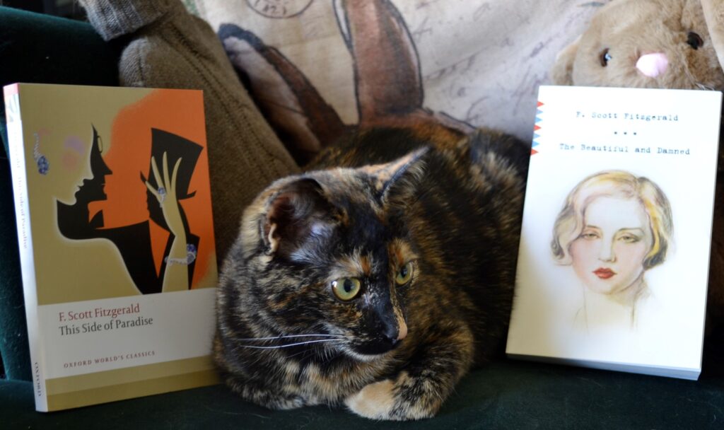 A tortoiseshell kitten sits beside two books by the Fitzgeralds.