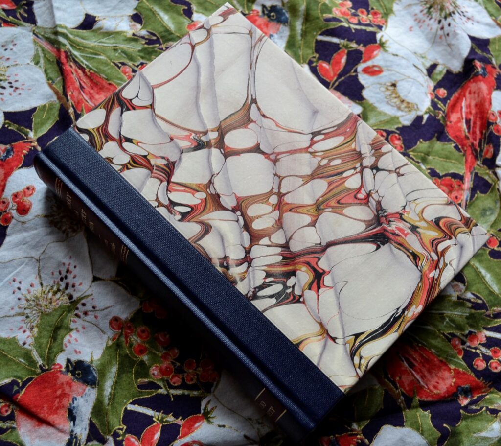 A marbled book with a blue spine sits on a floral background.