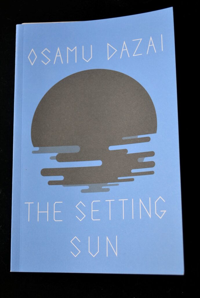 A blue book with a black silhouette of a sun setting over the water.