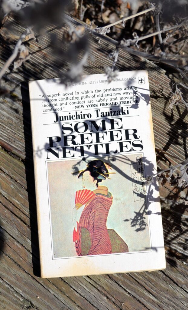A copy of Some Prefer Nettles lies beneath the shadow of a dead plant.