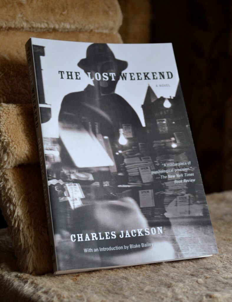 On a book titled 'The Lost Weekend' by Charles Jackson, there is a black-and-white silhouette of a man over a shop window.