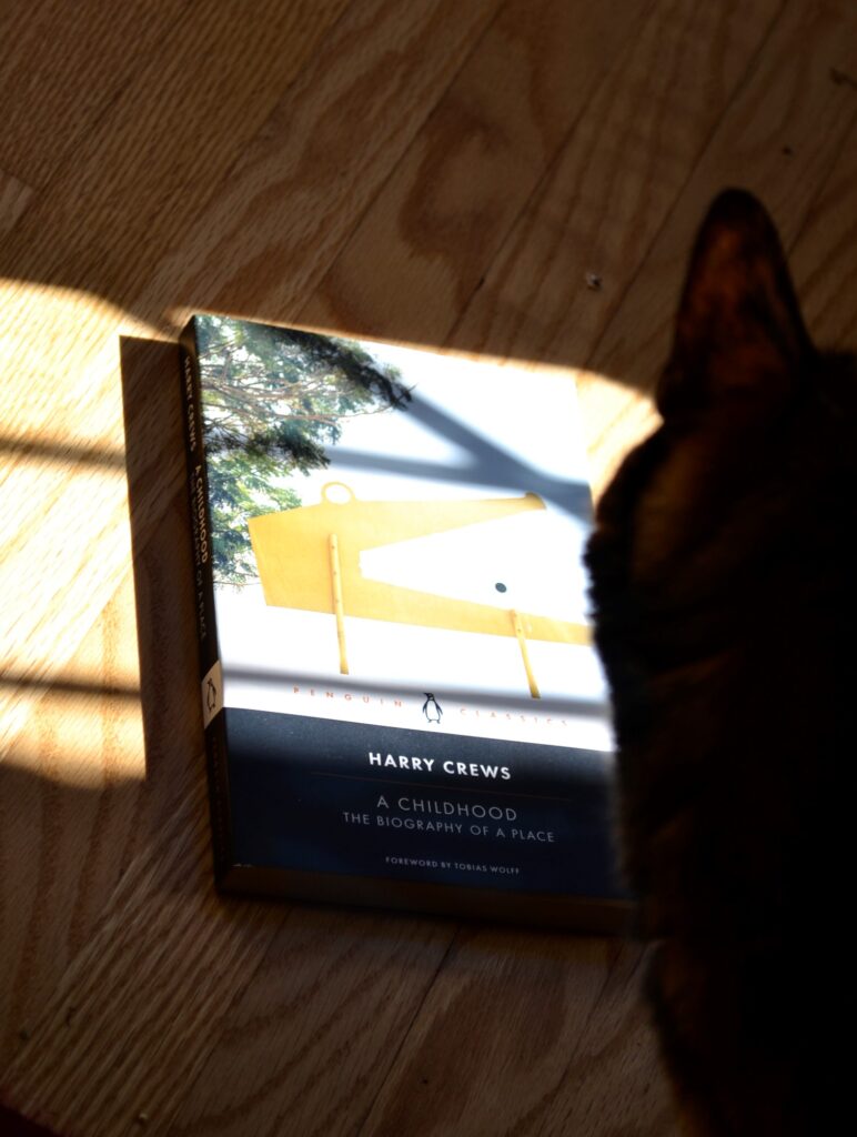 The silhouette of a cat's ear overlaps Harry Crews' A Childhood.