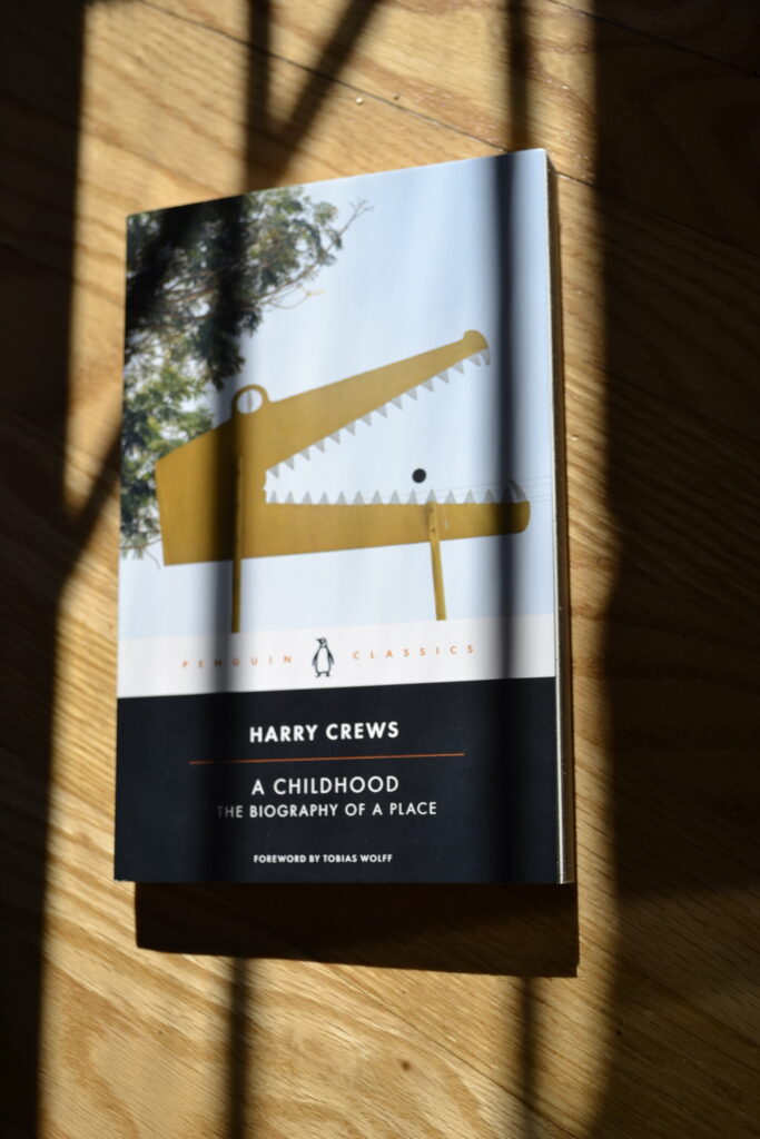 A yellow silhouette of a crocodile with its jaws open is the cover image for Harry Crews' A Childhood.
