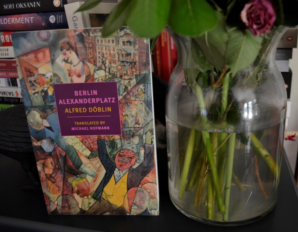 Beisde a jar of flowers sits a copy of Berlin Alexanderplatz.