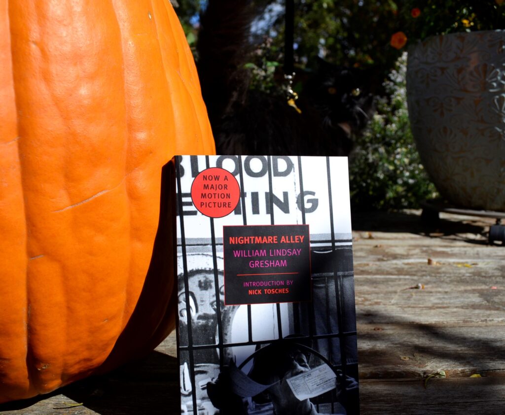 A copy of Nightmare Alley by William Lindsay Gresham leans on a pumpkin.