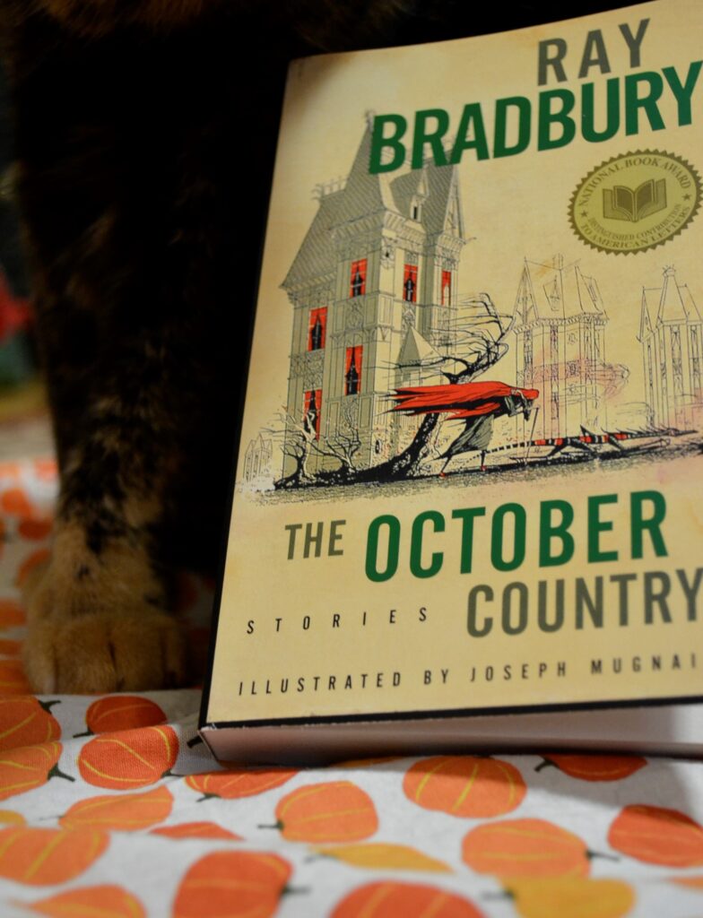 Ray Brandbury's The October Country features a person and a creature in the wind in front of gothic houses.