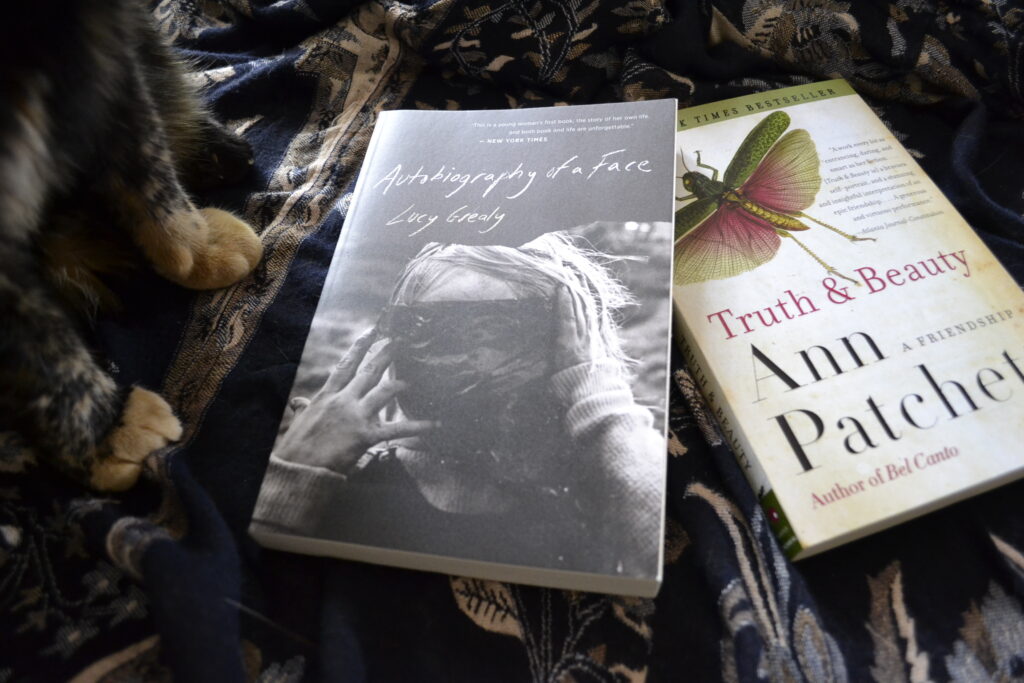 Lucy Grealy's Autobiography of a Face and Ann Patchett's Truth & Beauty lie stacked beside a pair of cat's paws.