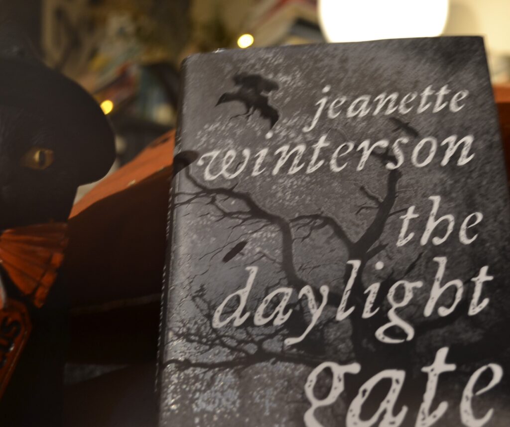 The Daylight Gate by Jeannette Winterson has a silver-grey cover with silhouettes of leaf-bare trees and crows.
