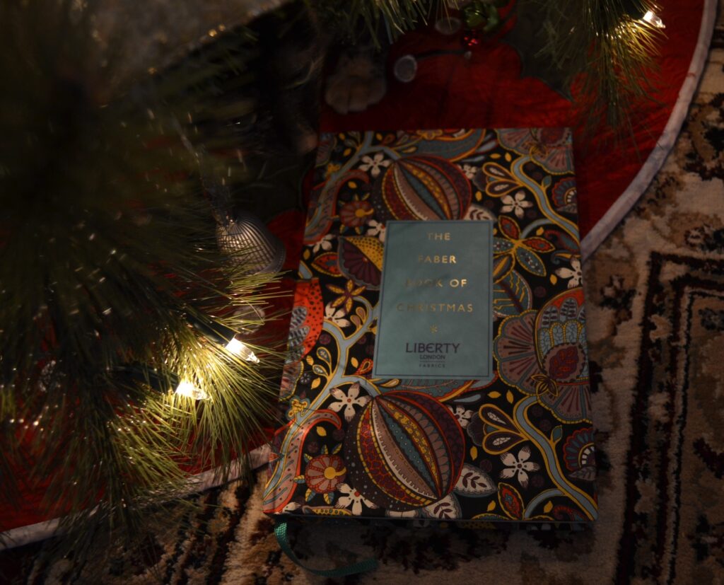 The Faber Book of Christmas has a hard cover wrapped in the print of a vintage fabric: vines, striped balls, and flowers in many colours, especially blue, yellow, purple, and orange.
