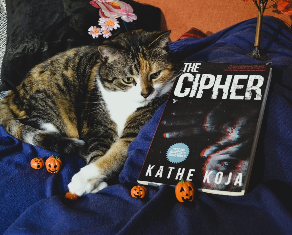 Kathe Koja's The Cipher has a cover that shows a person holding up a bloody hand in the dark.