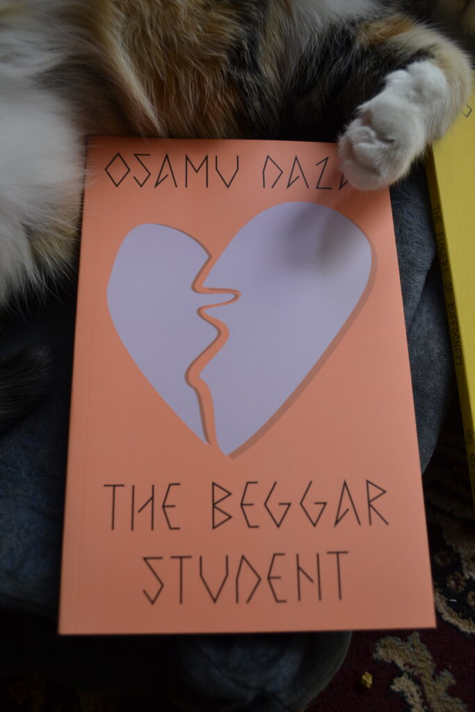 Osamu Dazai's The Beggar Student is an orange paperback book with a picture of a cut-out of a paper heart split down the middle.