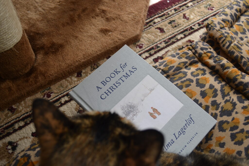A Book for Christmas is a small grey cloth-bound hardcover book by Selma Lagerlöf. The inset picture is a snow-covered, white skied landscape with two figures in bright Swedish winter wear holding hands.