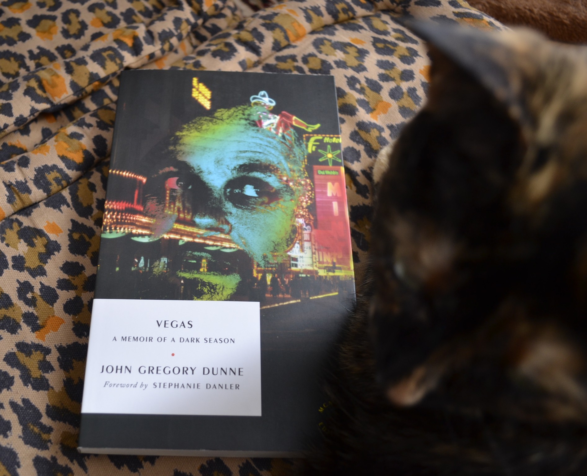 Vegas: A Memoir of a Dark Season by John Gregory Dunne is a softcover book with a dark cover and overlaid neon images.