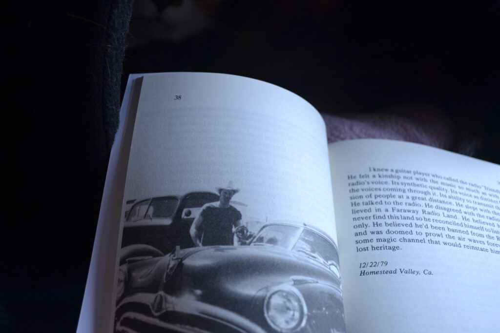 An open book shows a picture of a man in a cowboy hat by a 50s car and a story that is half a page long.