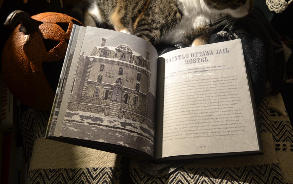 A book is open to a page showing a snow-covered four-storey building with two chimneys and a flat, imposing exterior. The opposite page shows text about Saintlo Ottawa Jail Hostel.